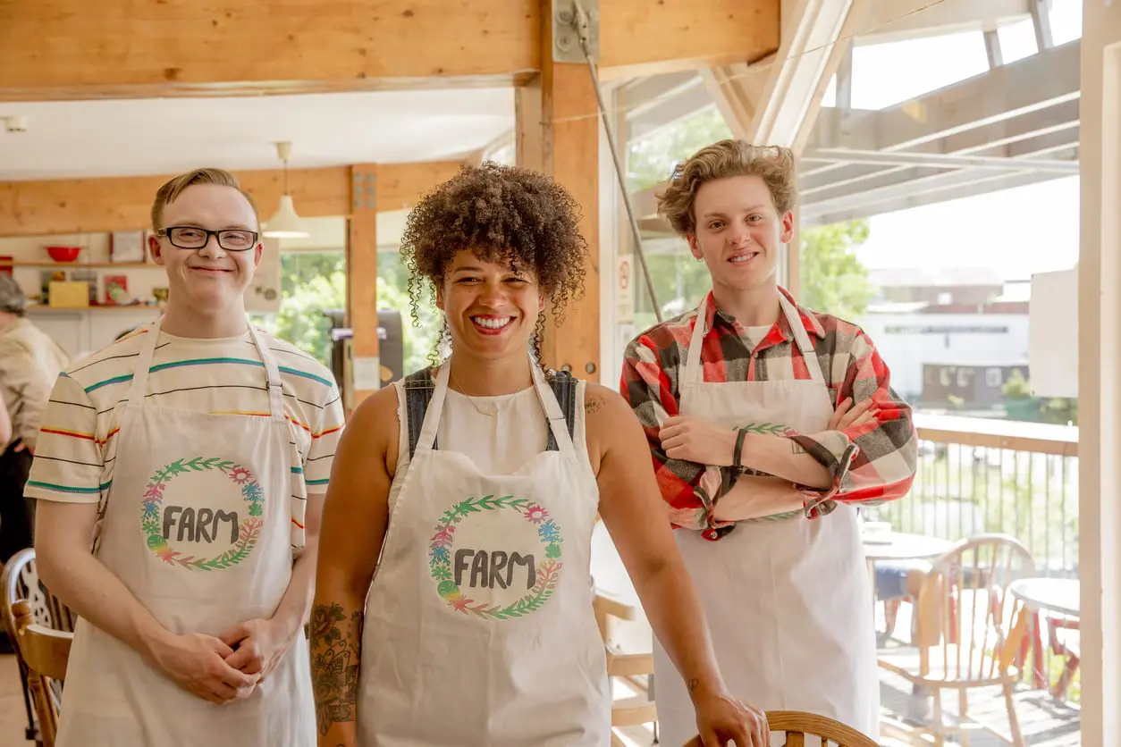 three people smiling in apronss with a farm logo on them