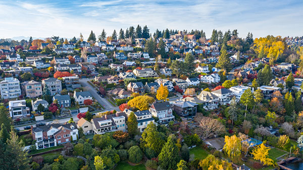 A neighborhood view in the early fall with trees and a blue sky with clouds