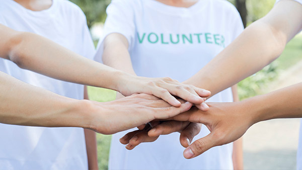 A nonprofit group working together and putting their hands in a circle to show teamwork