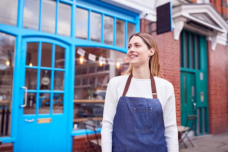 Smiling woman standing outside of her retail business