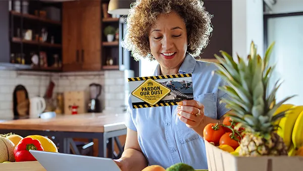 A woman reading a home services direct mail postcard at home