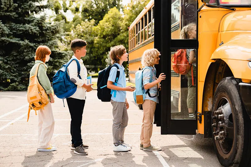 kids lined up to go on a yellow bus on the first day of school
