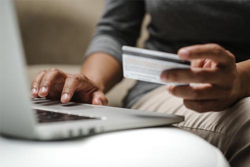 up close view of someone with a credit card and laptop doing online shopping
