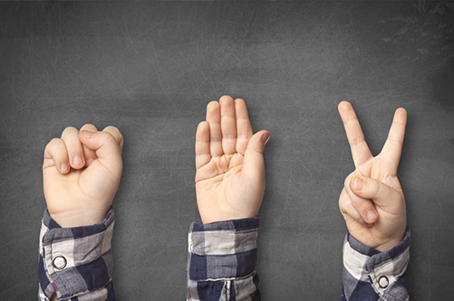 hands over a chalkboard background doing the rock paper scissors game